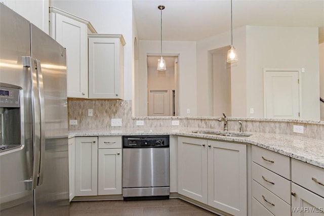 kitchen featuring appliances with stainless steel finishes, backsplash, decorative light fixtures, light stone countertops, and a sink