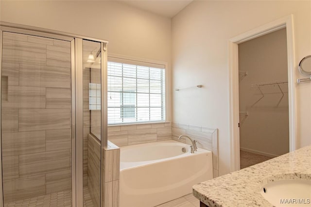 bathroom featuring a spacious closet, a garden tub, vanity, and a shower stall