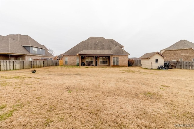 rear view of house with a fenced backyard, brick siding, and a lawn