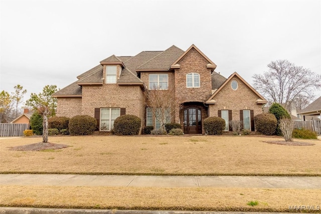 traditional home with fence, a front lawn, french doors, and brick siding