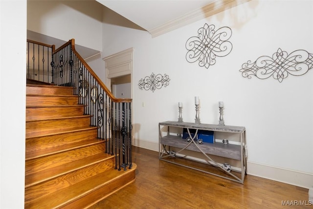 stairs featuring crown molding, vaulted ceiling, wood finished floors, and baseboards