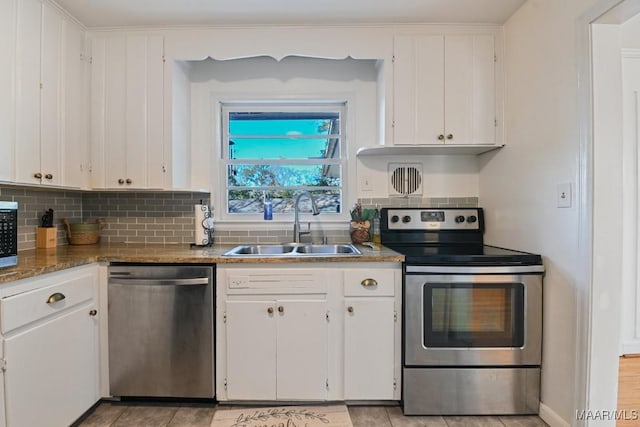 kitchen featuring stainless steel appliances, white cabinetry, a sink, and decorative backsplash