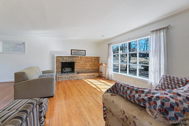 living area featuring ornamental molding, a fireplace with raised hearth, and wood finished floors