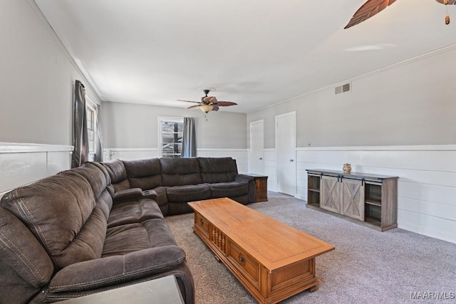 living area with a ceiling fan, carpet, wainscoting, and visible vents