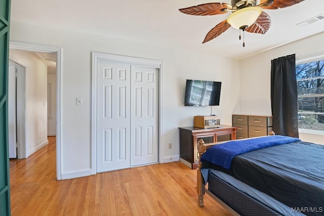 bedroom with ceiling fan, visible vents, baseboards, light wood-style floors, and a closet