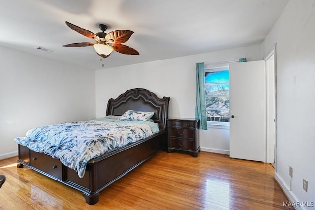 bedroom featuring a ceiling fan, light wood-type flooring, visible vents, and baseboards