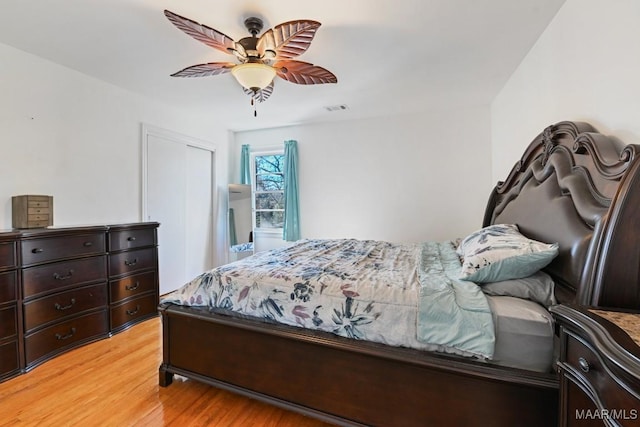 bedroom with light wood-type flooring, a closet, visible vents, and ceiling fan