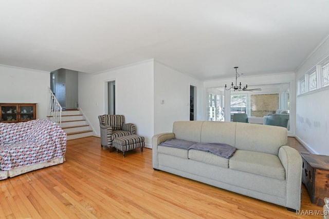 living area featuring an inviting chandelier, light wood-style flooring, stairway, and crown molding