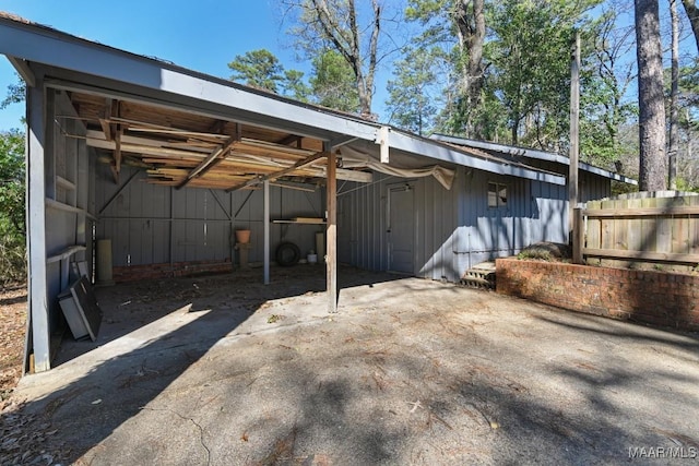 view of vehicle parking with a carport, fence, and driveway