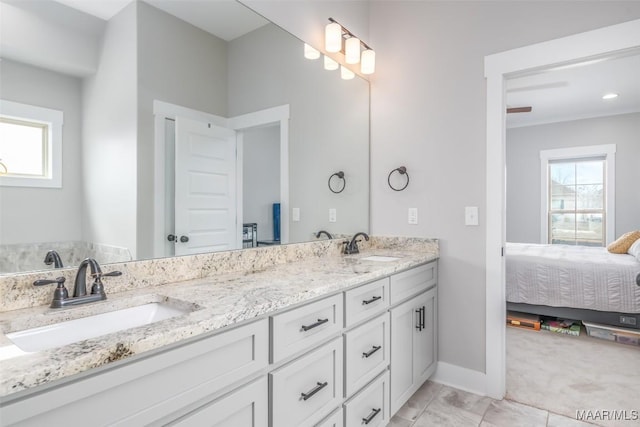 ensuite bathroom featuring ensuite bathroom, double vanity, a sink, and a healthy amount of sunlight