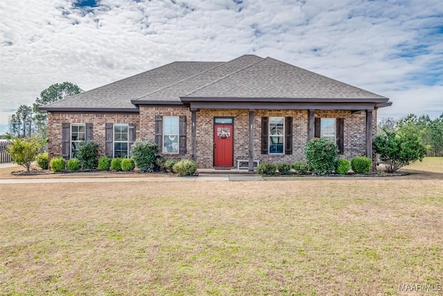 view of front of house featuring brick siding, a front lawn, and roof with shingles