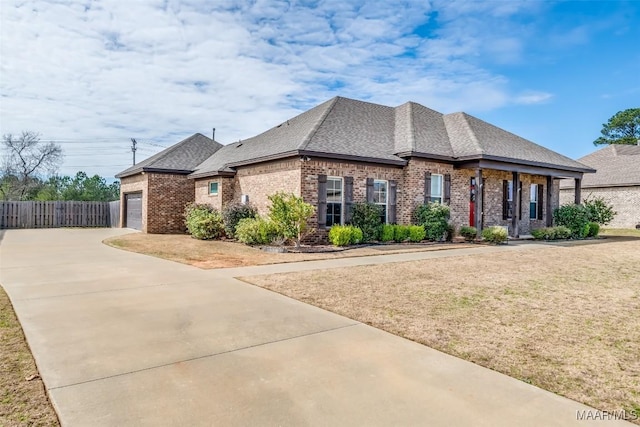 view of front of home featuring brick siding, roof with shingles, concrete driveway, fence, and a garage