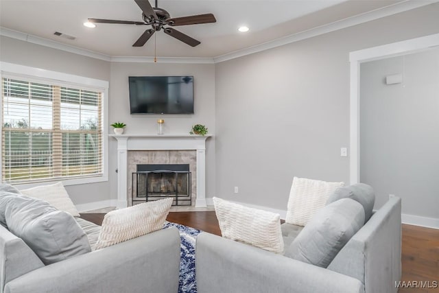 living area with a fireplace, visible vents, wood finished floors, and ornamental molding