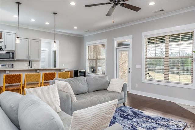 living room featuring recessed lighting, dark wood-style flooring, visible vents, baseboards, and ornamental molding