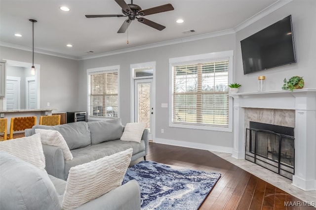 living room with light wood-type flooring, visible vents, a tiled fireplace, and ornamental molding