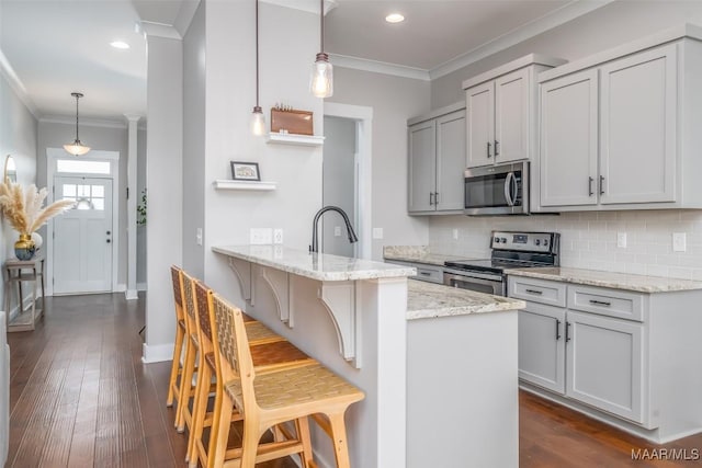 kitchen featuring decorative light fixtures, a breakfast bar area, stainless steel appliances, light stone countertops, and a peninsula