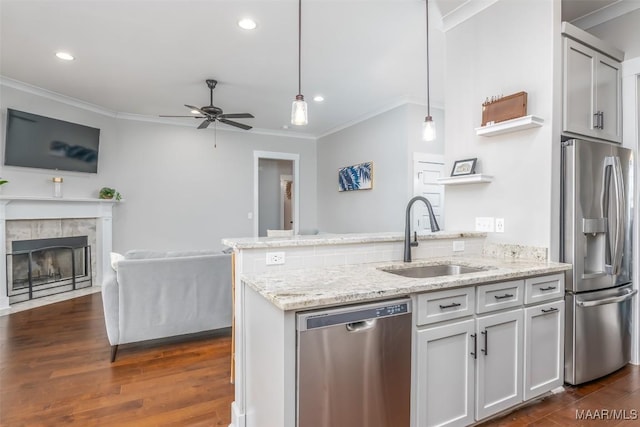 kitchen with decorative light fixtures, crown molding, appliances with stainless steel finishes, open floor plan, and a sink