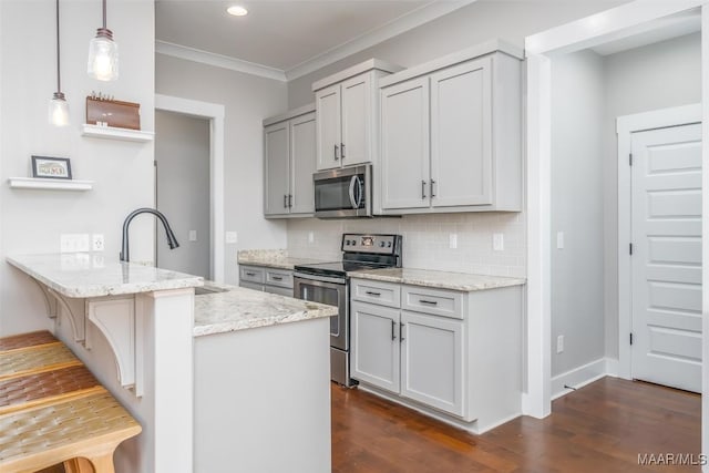 kitchen featuring stainless steel appliances, hanging light fixtures, light stone countertops, a peninsula, and a kitchen breakfast bar