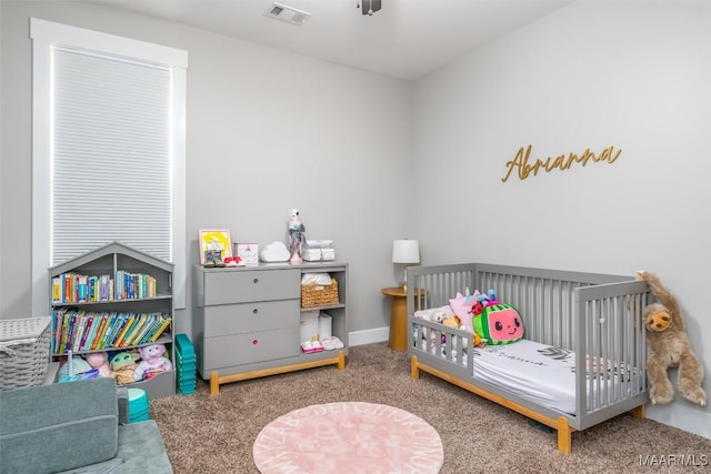 carpeted bedroom featuring a nursery area and visible vents