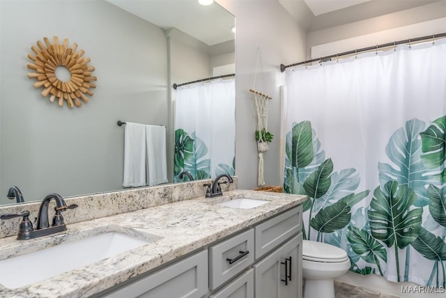 full bath with double vanity, a sink, and toilet