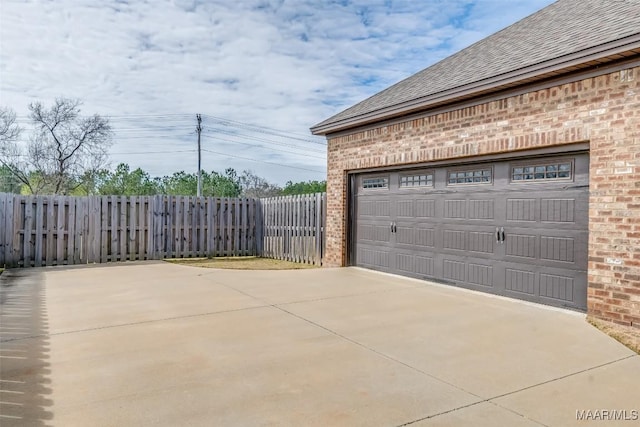 garage featuring driveway and fence