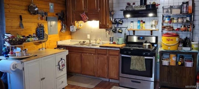 kitchen with light countertops, backsplash, a sink, electric panel, and stainless steel gas range oven