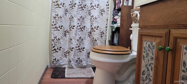 bathroom featuring toilet, a shower with curtain, and wood finished floors