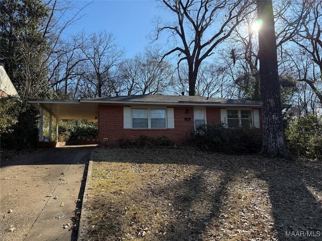 single story home featuring an attached carport, concrete driveway, and brick siding