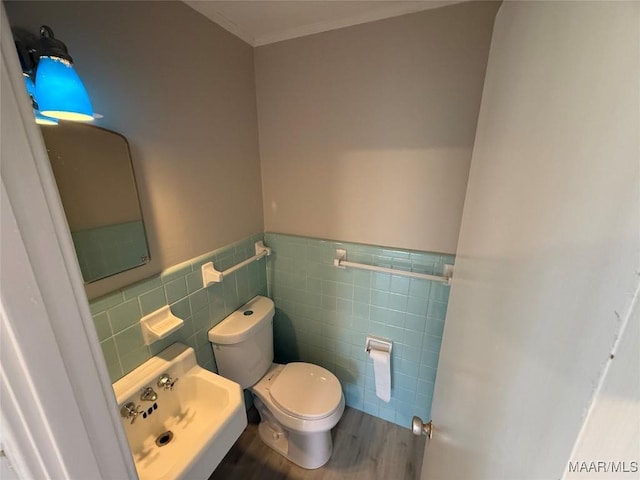 half bathroom featuring wainscoting, tile walls, toilet, and wood finished floors