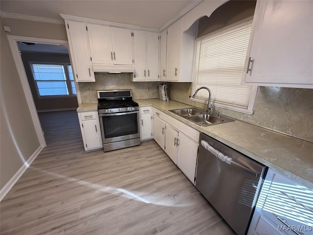 kitchen featuring a sink, white cabinetry, light countertops, appliances with stainless steel finishes, and crown molding