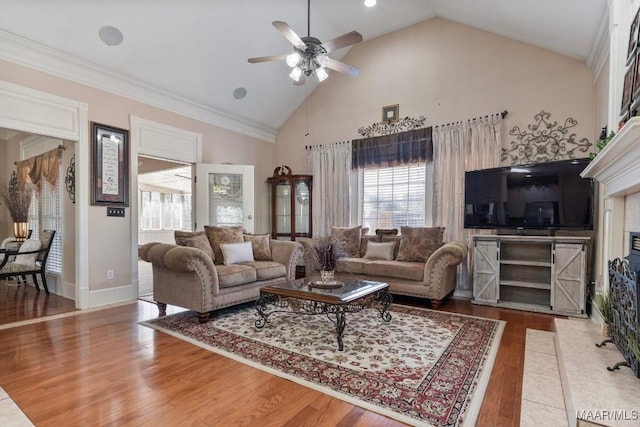 living area featuring baseboards, ceiling fan, high vaulted ceiling, and wood finished floors