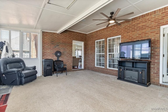 living room featuring a wood stove, light colored carpet, a fireplace, and brick wall