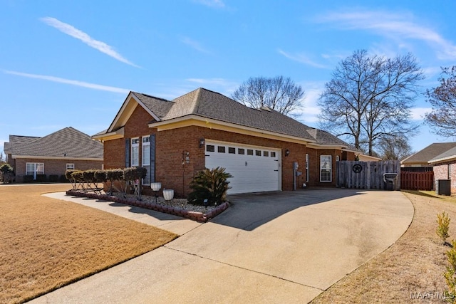 view of home's exterior with brick siding, a shingled roof, concrete driveway, an attached garage, and fence