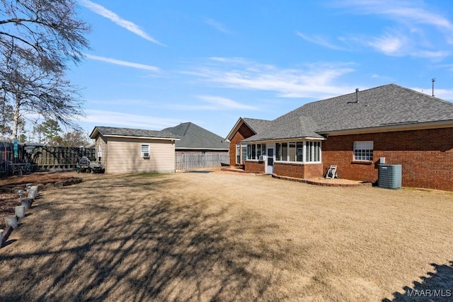 back of house featuring brick siding, fence, an outdoor structure, and a lawn