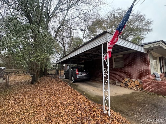 view of side of home featuring driveway, an attached carport, fence, and brick siding