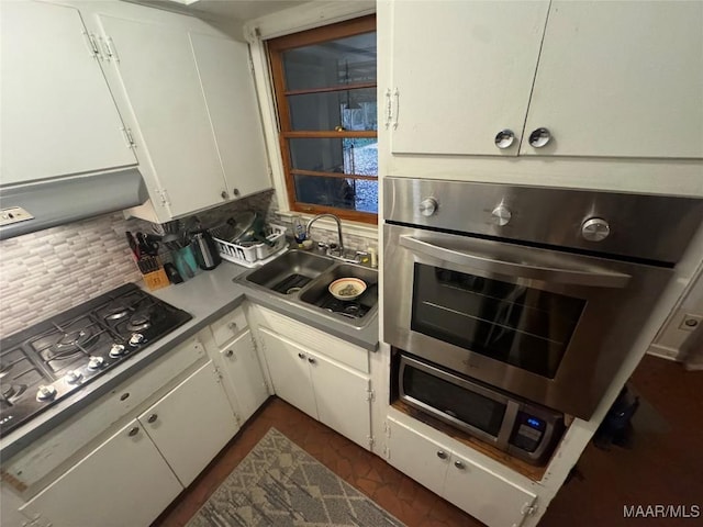 kitchen featuring appliances with stainless steel finishes, backsplash, a sink, and white cabinetry