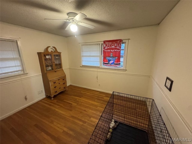 miscellaneous room featuring a textured ceiling, ceiling fan, dark wood finished floors, and baseboards