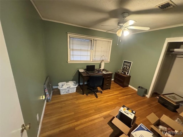 home office with visible vents, light wood-style floors, ornamental molding, ceiling fan, and baseboards