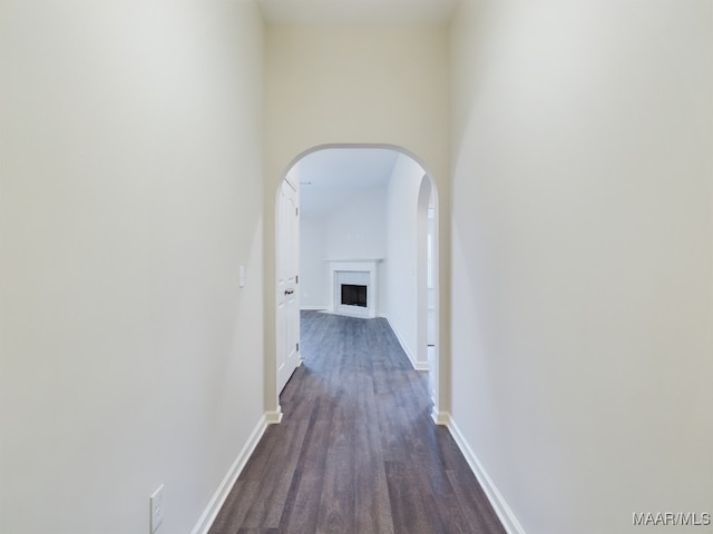 hall with baseboards, arched walkways, and dark wood finished floors