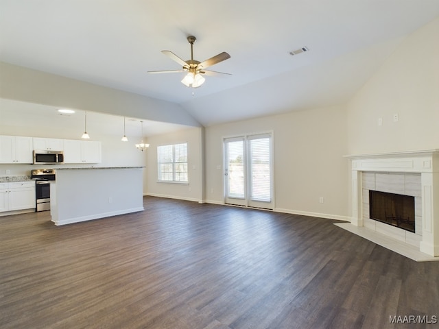 unfurnished living room with lofted ceiling, visible vents, dark wood-type flooring, a tile fireplace, and ceiling fan with notable chandelier