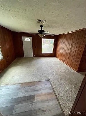 4325 Zorn Ln, Montgomery, AL 36116 - unfurnished living room with plenty of natural light, wooden walls, visible vents, and a ceiling fan
