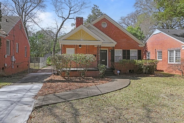 bungalow-style home with brick siding, fence, concrete driveway, a chimney, and a front yard