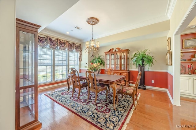 dining space featuring baseboards, visible vents, an inviting chandelier, crown molding, and light wood-style floors