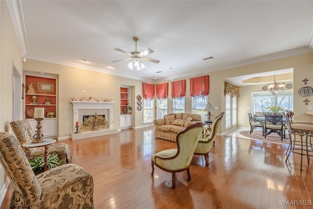 living room with light wood finished floors, a tile fireplace, visible vents, and crown molding