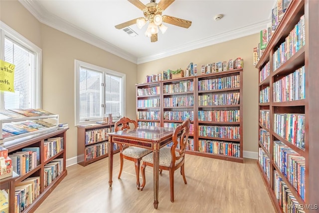 sitting room with visible vents, crown molding, and wall of books