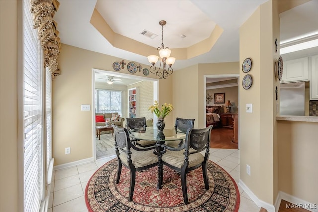 dining room with visible vents, a tray ceiling, a chandelier, and light tile patterned flooring