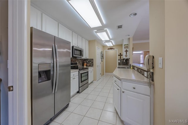 kitchen with white cabinets, decorative backsplash, stainless steel appliances, light countertops, and light tile patterned flooring