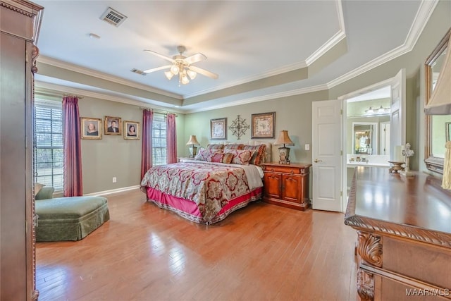 bedroom featuring light wood-style flooring, crown molding, visible vents, and a tray ceiling