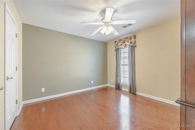 spare room featuring light wood finished floors, ceiling fan, visible vents, and baseboards