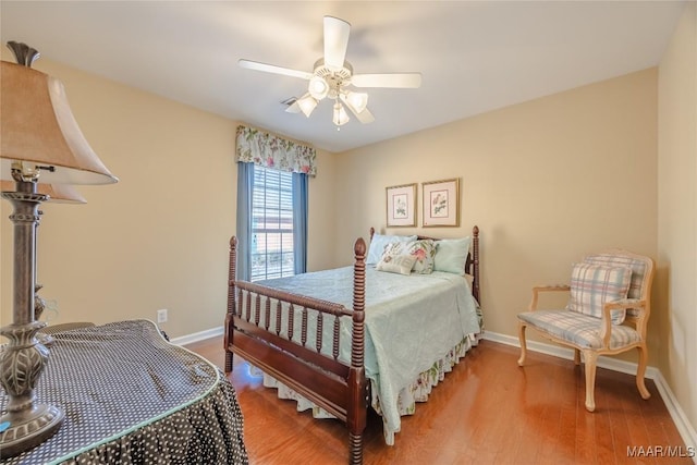 bedroom with ceiling fan, wood finished floors, and baseboards